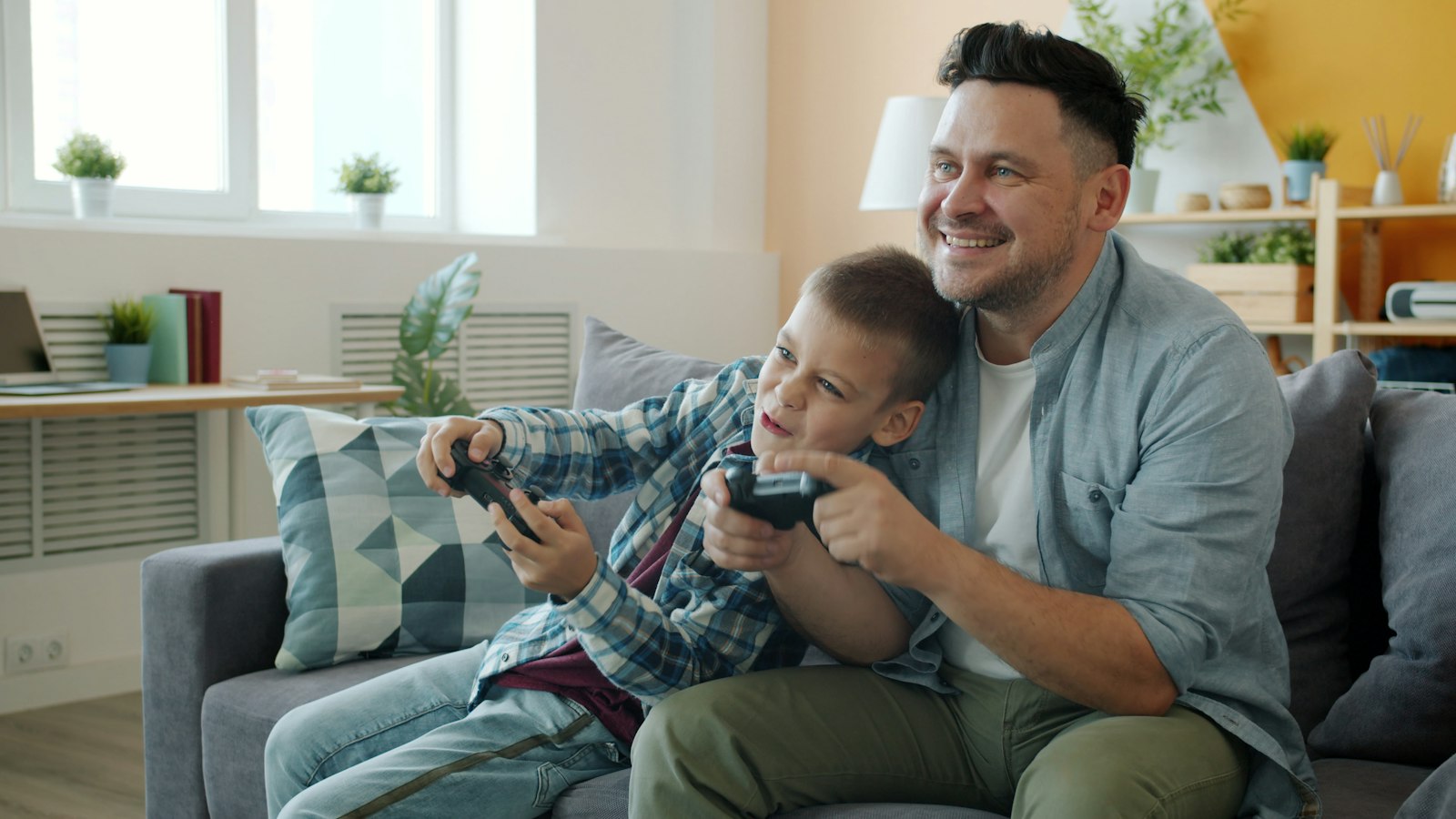 A father and son sharing a games console on the sofa, with the hours adding up