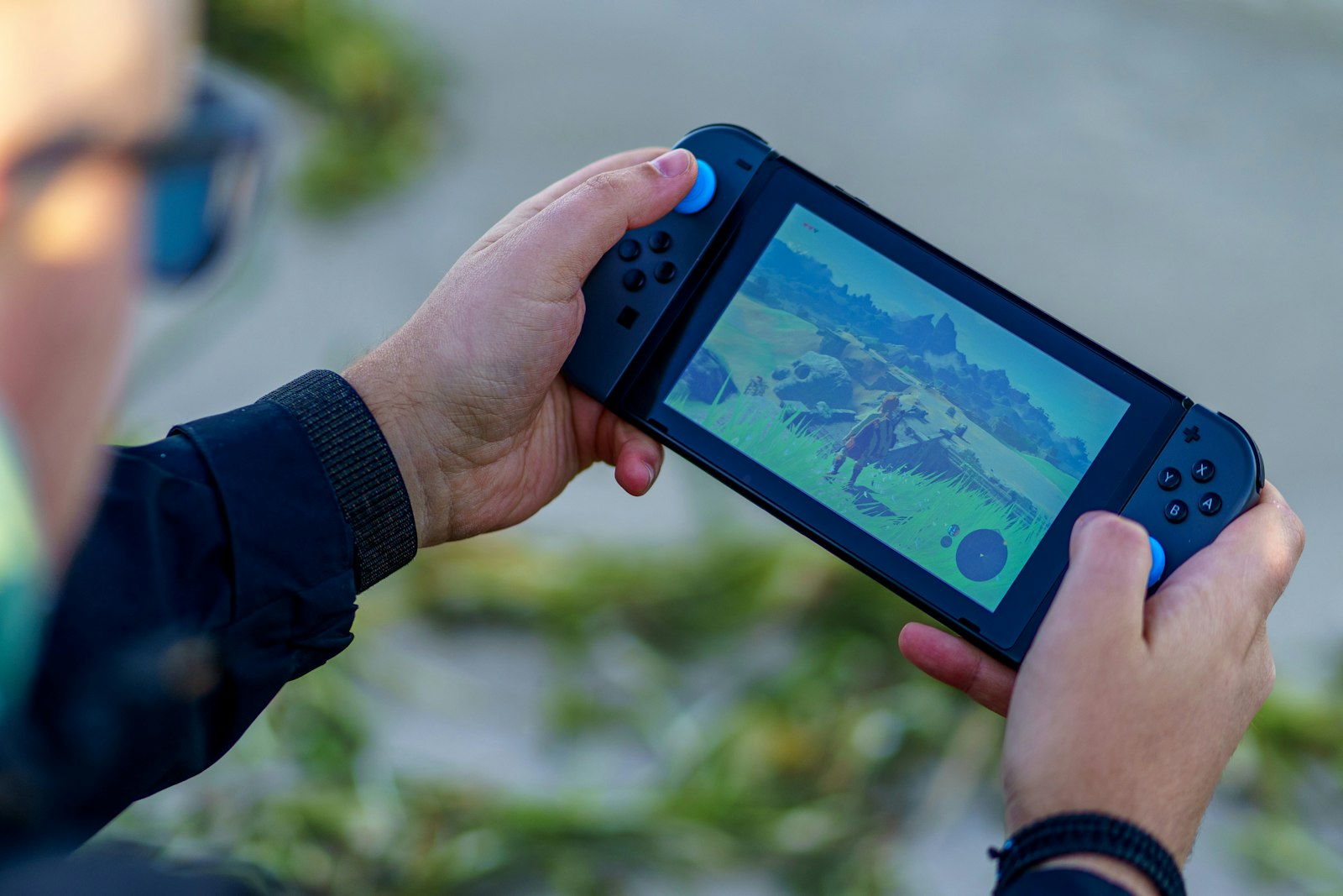Person playing a Nintendo Switch outdoors, one way to find time to play games in short sessions
