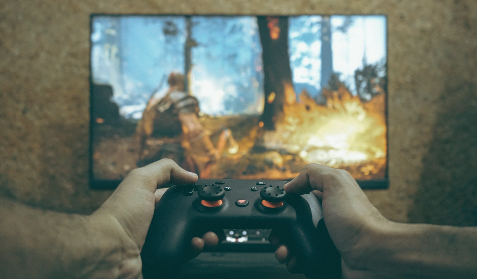 Hands holding a game controller in front of a TV, the kind of evening the fall game release season is built around